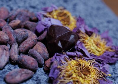 Petit cœur en chocolat artisanal bio Mana Lotos – Loving Kindness, avec fèves de cacao Criollo, posé sur une fleur de lotus séchée.