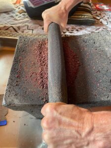 Fèves de cacao concassées (cacao nibs) sur un metate en pierre traditionnel. Les fèves de cacao concassées, appelées cacao nibs, sont présentées sur un metate en pierre, un outil traditionnel utilisé depuis des siècles pour broyer le cacao.