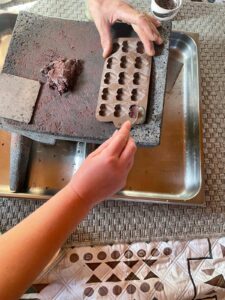 Mains remplissant des moules en forme de cœur avec du chocolat bean to bar, préparé sur un metate selon une tradition ancestrale.