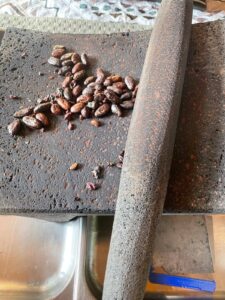 des fèves de cacao décortiquées posées sur un metate en pierre traditionnel.